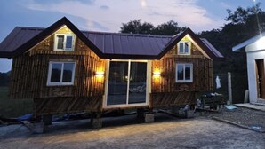 A wooden cabin with a metal roof, two windows, and a door. - Tres Marias Farmhouse with Pool (Cuyapo)