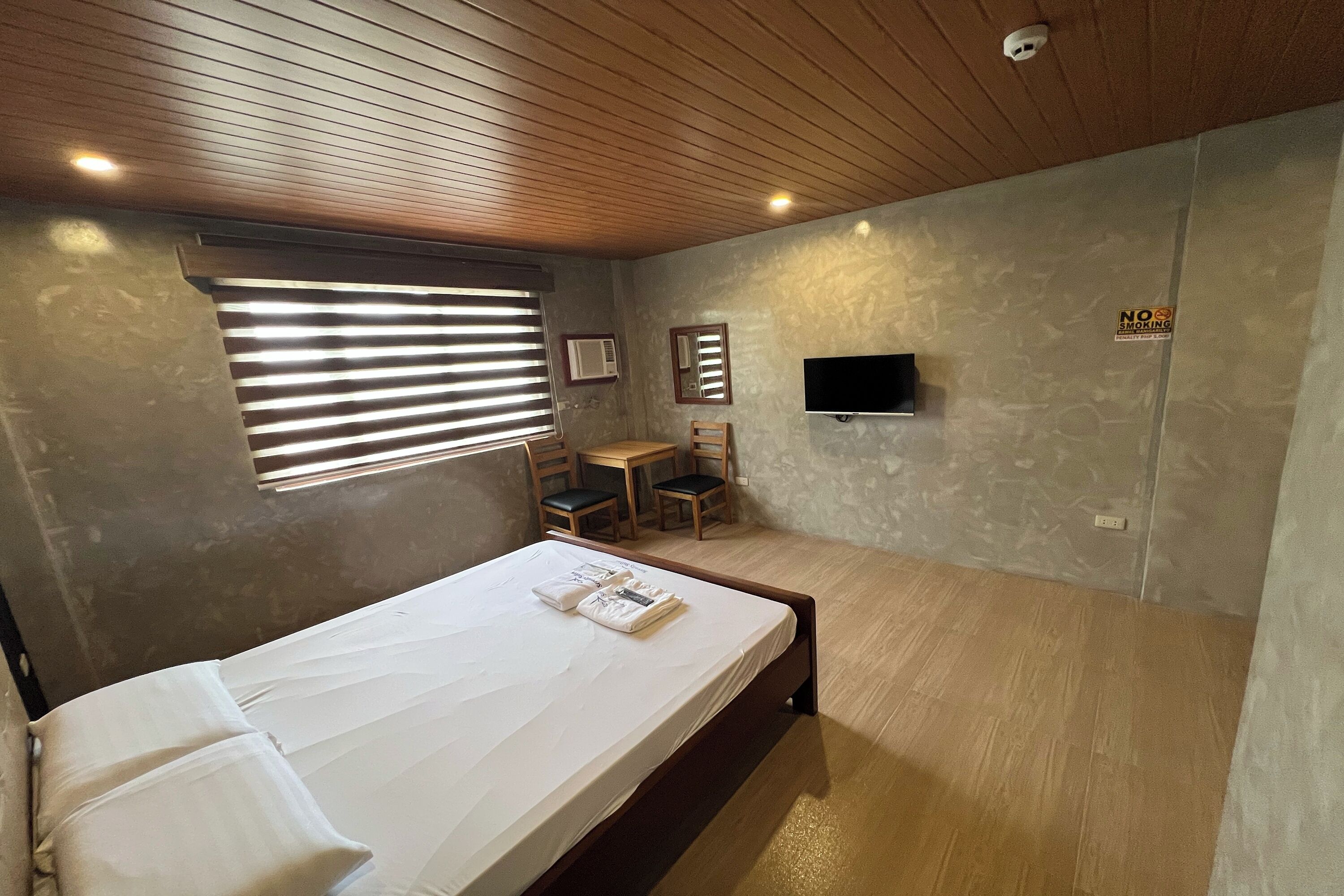 Quarto com cama, escrivaninha e televisão.