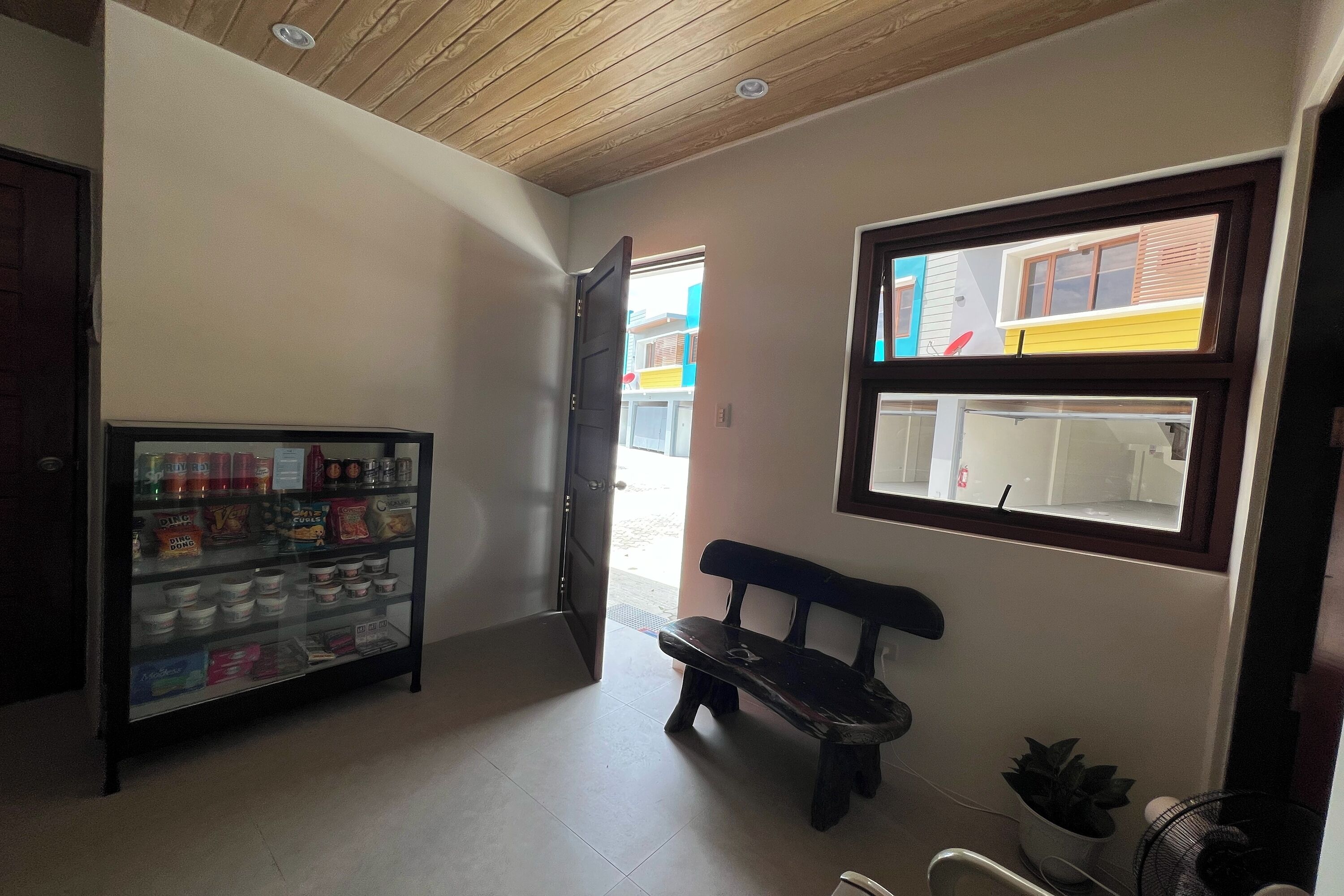 A hallway with a vending machine, a bench, a window with a view of buildings, and a door leading outside.