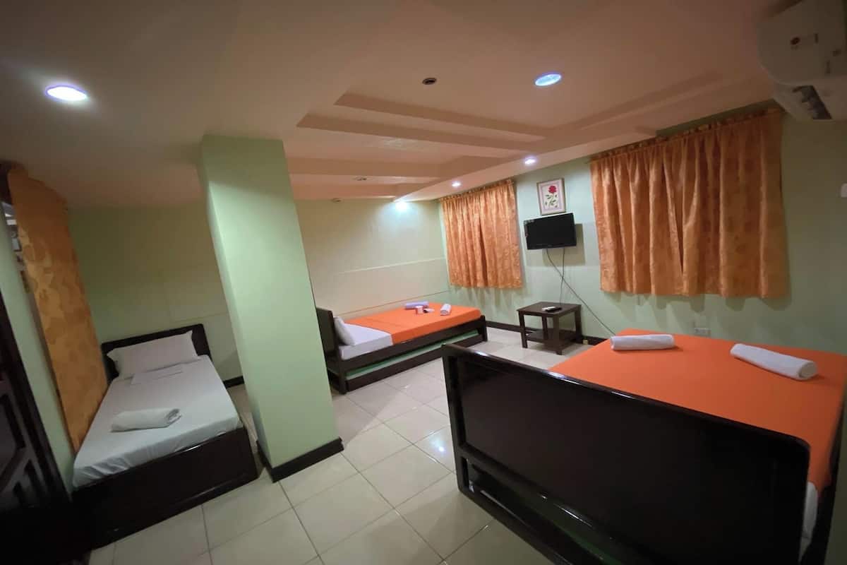 A hotel room with two beds, a TV, and a small table.