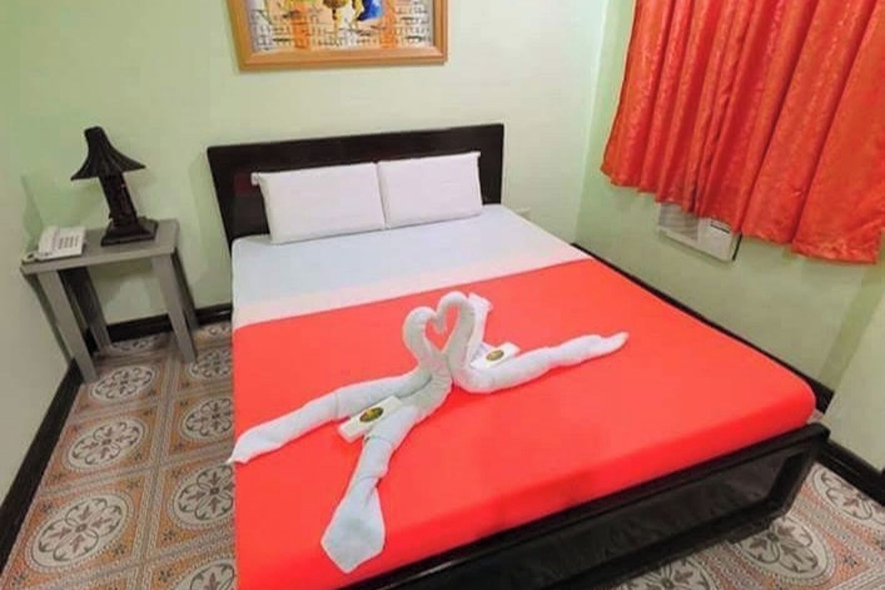 Une chambre d’hôtel avec un lit, une table de chevet avec une lampe et un tableau au mur.