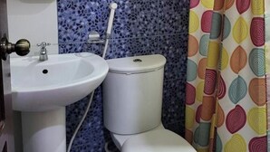 Une salle de bain avec un lavabo blanc, des toilettes et un rideau de douche à motifs.