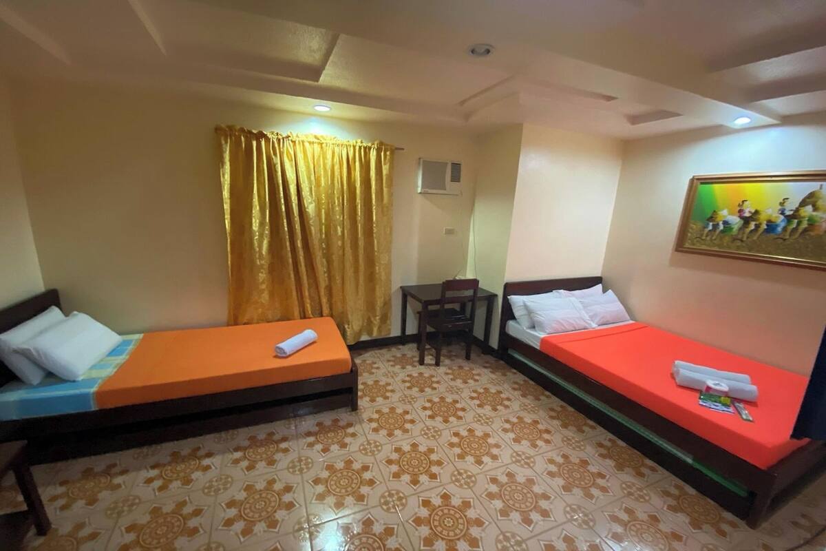 A room with two beds, a small table, and a chair.