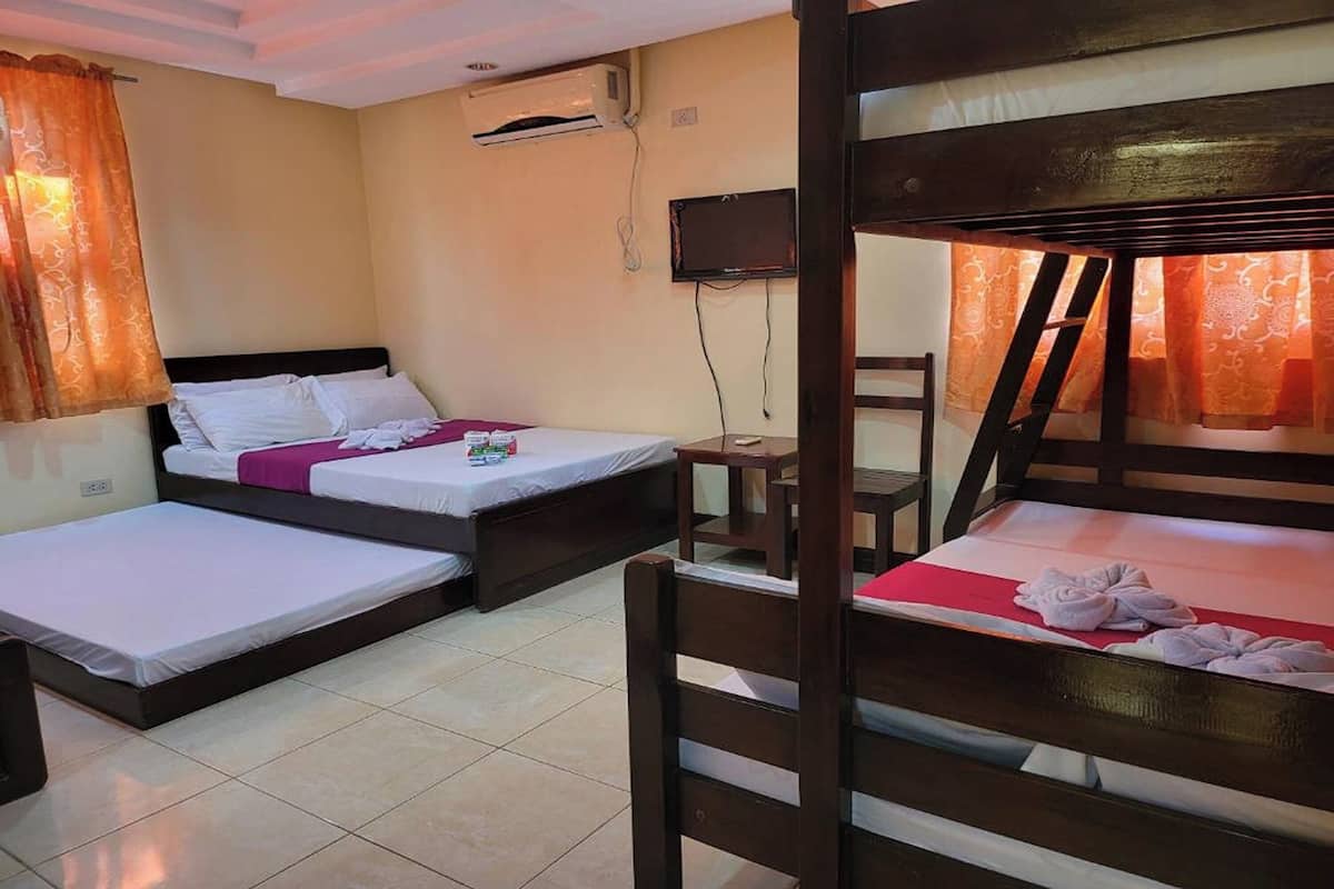 A room with two beds, a TV, and a window with curtains.