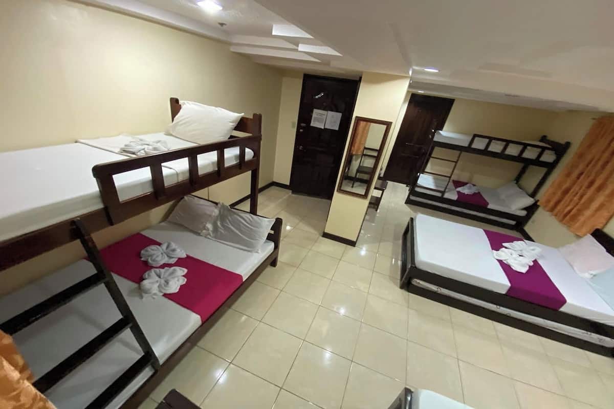 A hotel room with bunk beds, a mirror, and a tiled floor.