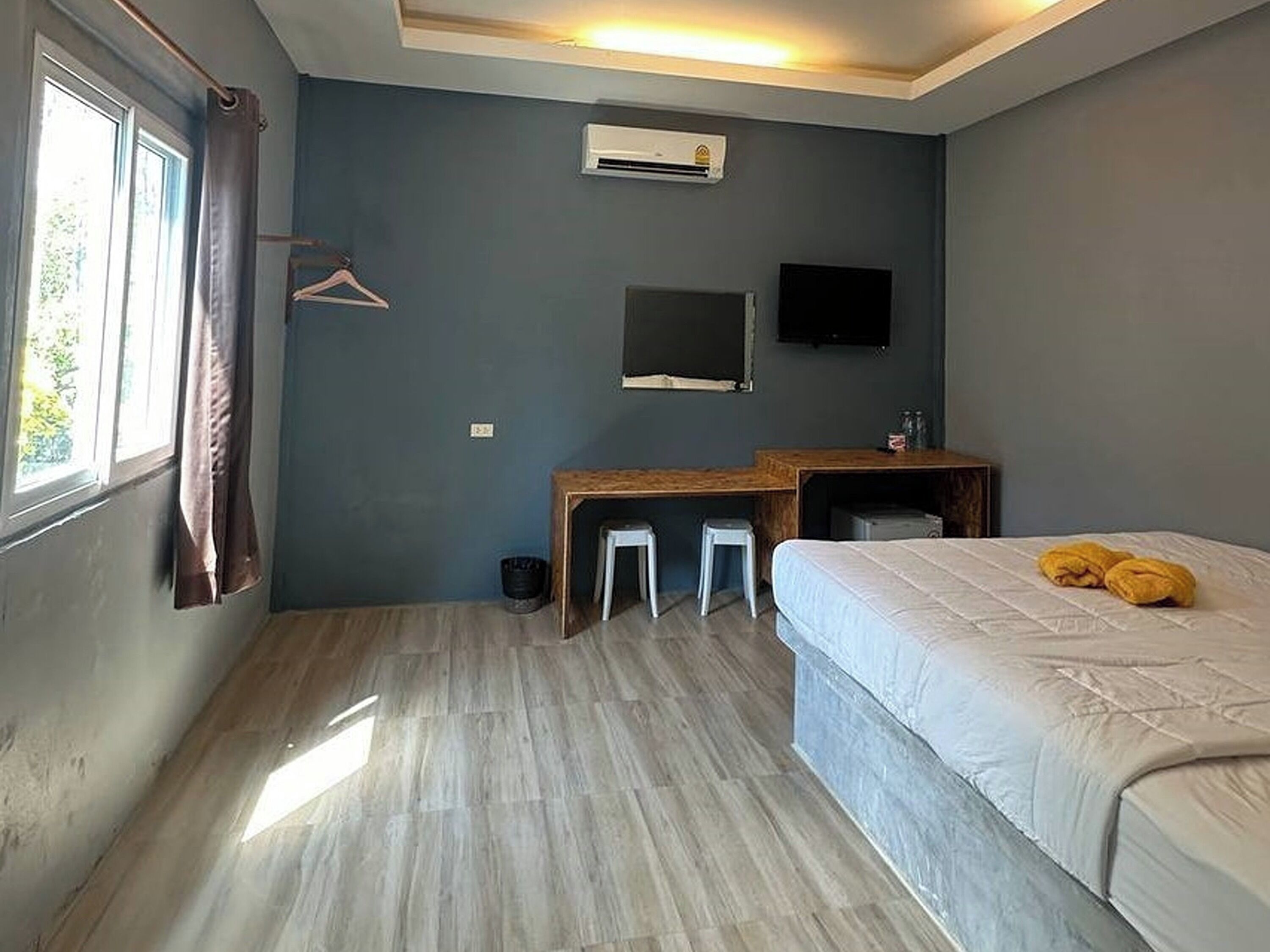 A room with a bed, a desk, a chair, a TV, and a window with curtains.