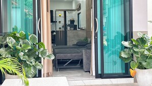Ein modernes Interieur mit einer Couch, einem Essbereich und einer durch eine Glastür einsehbarer Küche.