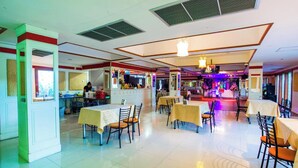 A spacious restaurant with multiple tables and chairs, a central bar area with colorful lighting, and a modern ceiling design. - Good View Residence (Lampang)