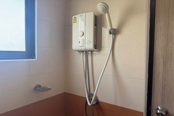 A shower unit with a control panel and a handheld showerhead mounted on the wall.