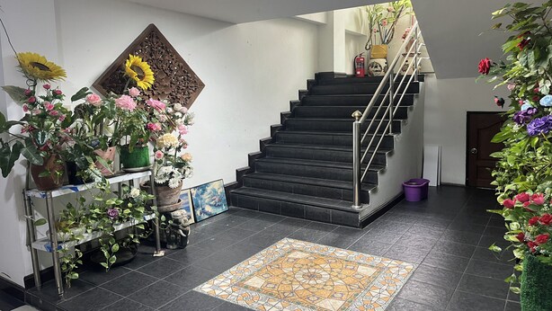 A staircase with a handrail, surrounded by potted plants and artwork. - Green Place 107 (Bangkok)