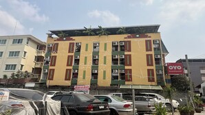 A multi-story building with a yellow facade, green accents, and multiple air conditioning units. - Green Place 107 (Bangkok)