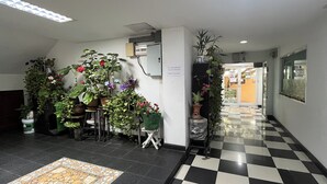 A hotel lobby with a checkered floor, potted plants, and a tiled area rug. - Green Place 107 (Bangkok)