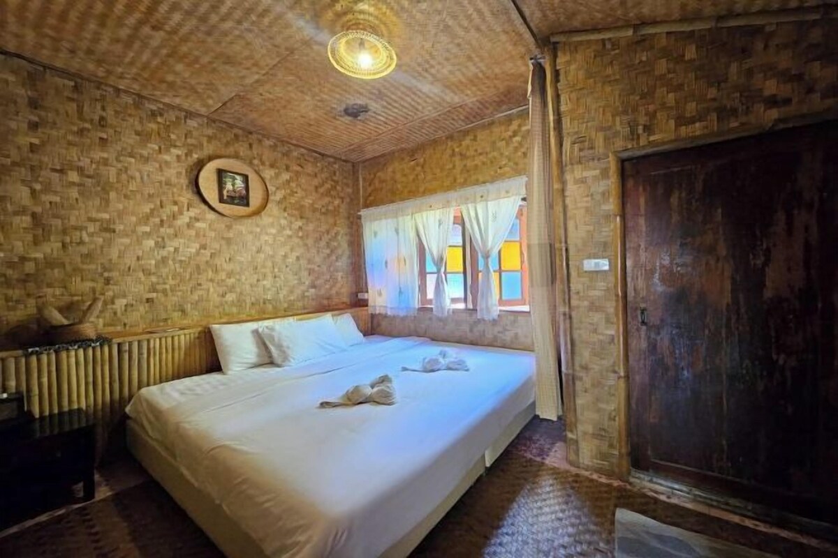 Een kamer met een bed, een houten deur en een raam met gordijnen.