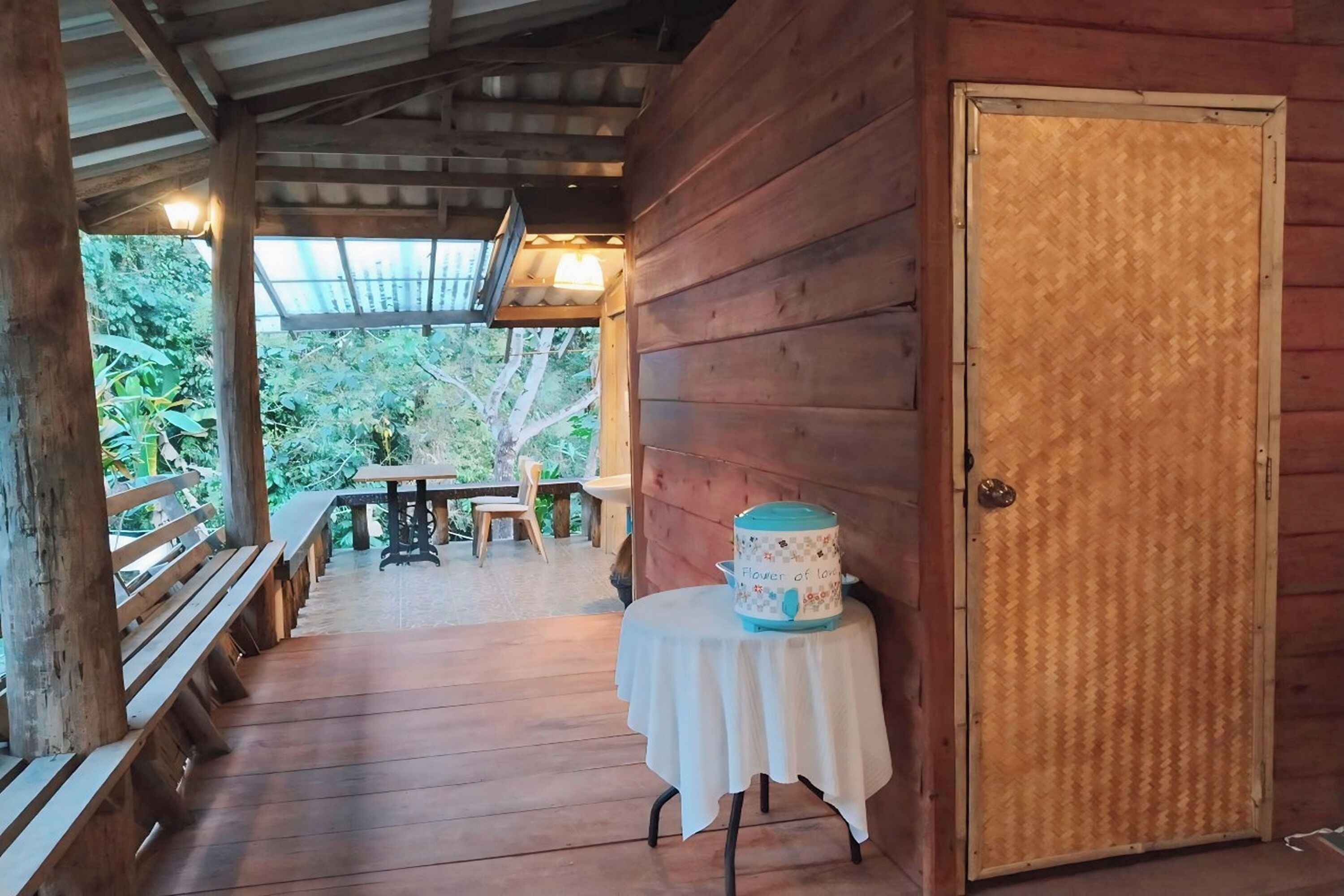 Une cabane en bois avec un porche, une table avec des chaises et un gâteau posé sur la table.