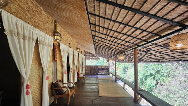 A covered outdoor seating area with wooden benches and a thatched roof. - Mae Mae Home (Chiang Dao)