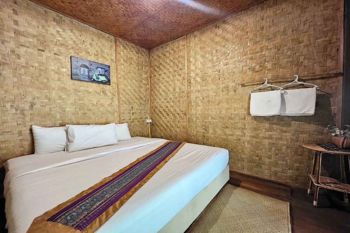 Una habitación con cama, un perchero de pared y una mesita con una planta.