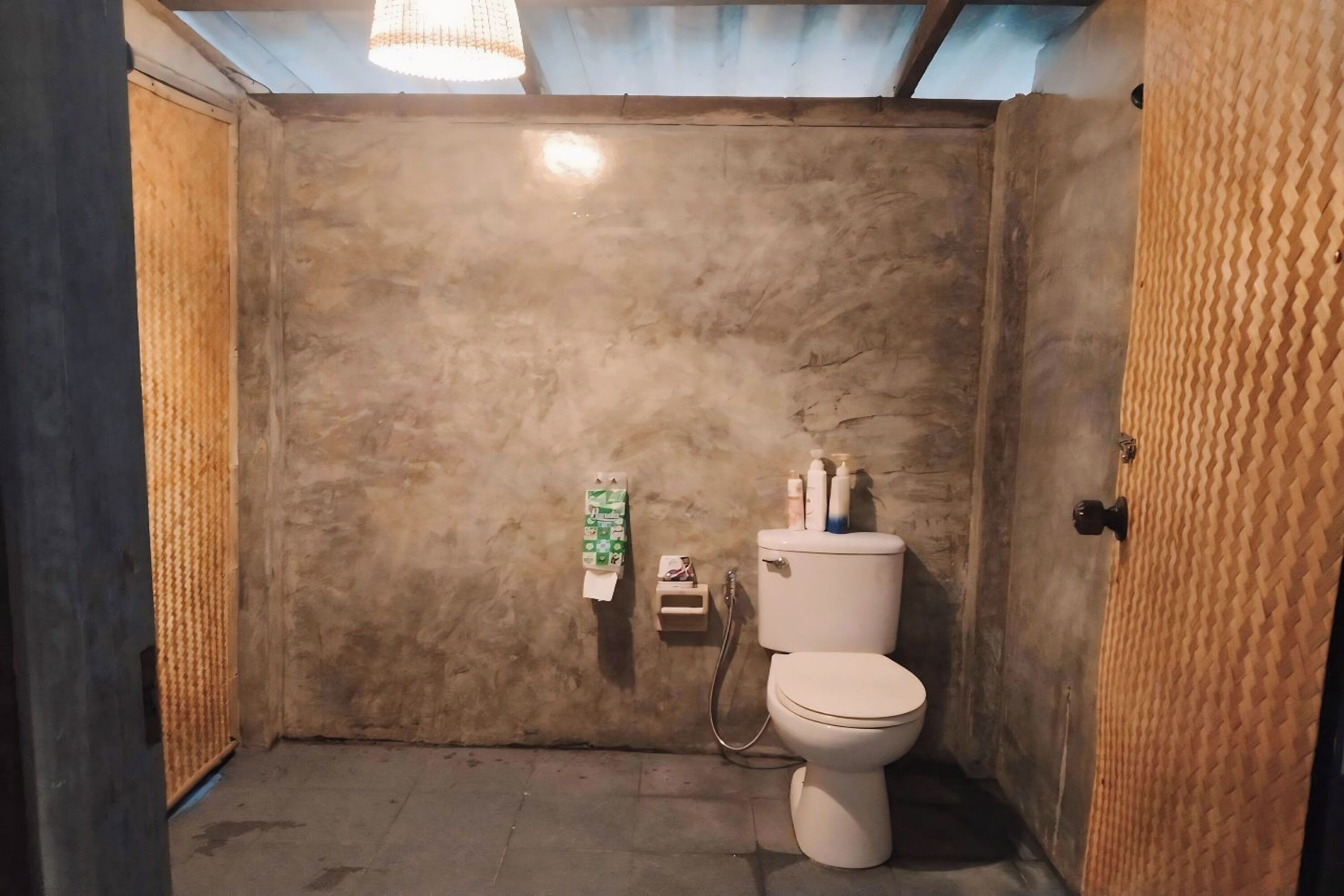 Une petite salle de bain compacte, équipée de toilettes, d’un distributeur de serviettes et d’un sèche-mains.