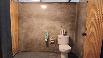 Une petite salle de bain compacte, équipée de toilettes, d’un distributeur de serviettes et d’un sèche-mains.