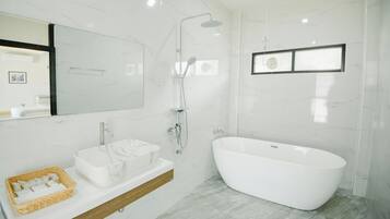 A modern bathroom with a freestanding bathtub, a vanity with a marble sink, and a shower with a handheld showerhead.