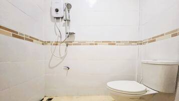A small, tiled bathroom with a toilet and a shower unit.