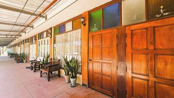 A covered corridor with wooden doors, benches, and potted plants.