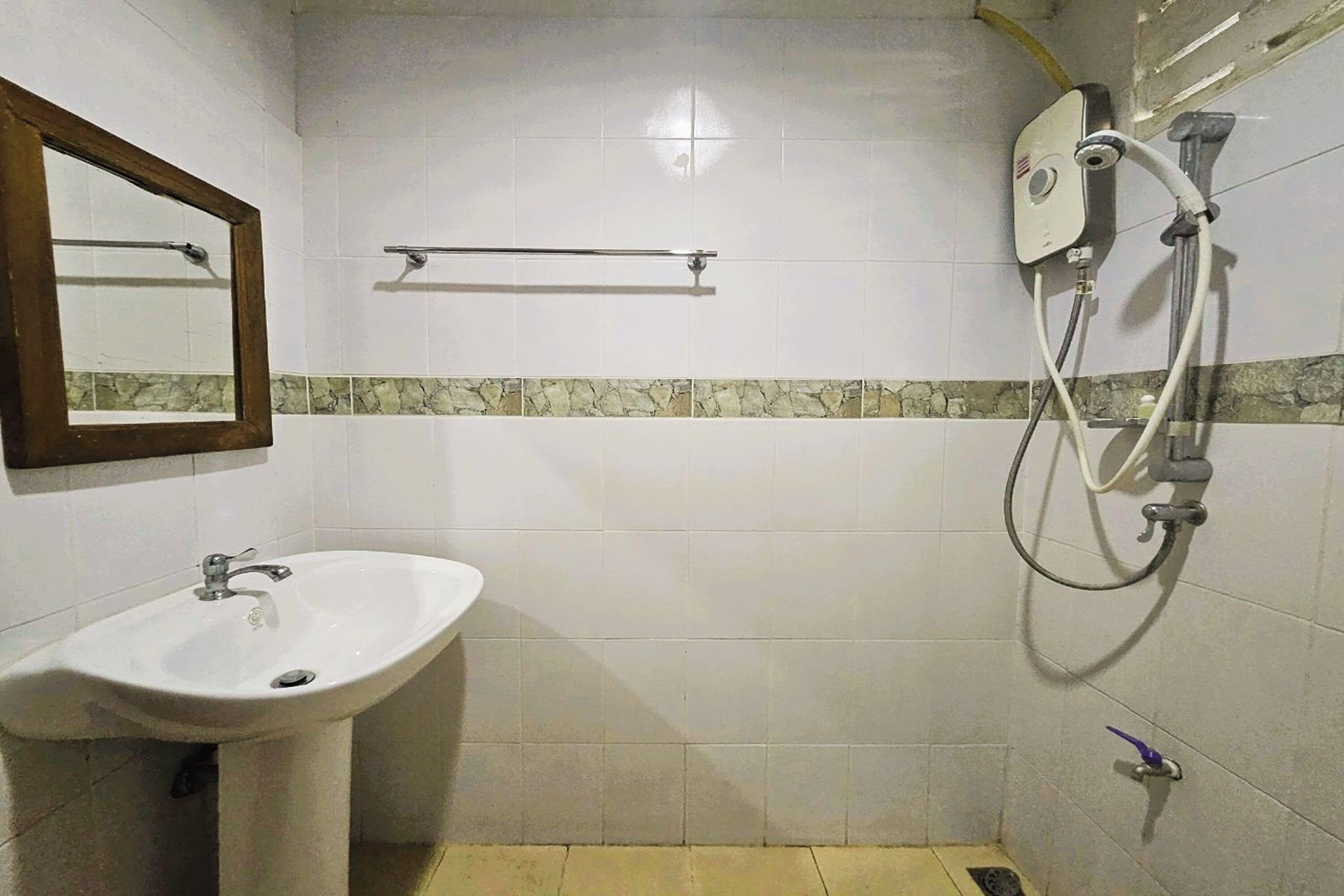 A bathroom with a sink, mirror, towel rack, and shower.