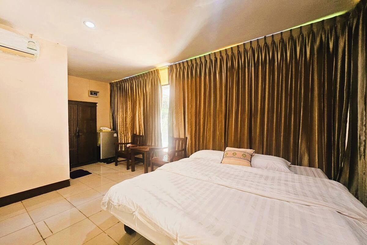 Ein Hotelzimmer mit Bett, Vorhängen, Schreibtisch und Stuhl.