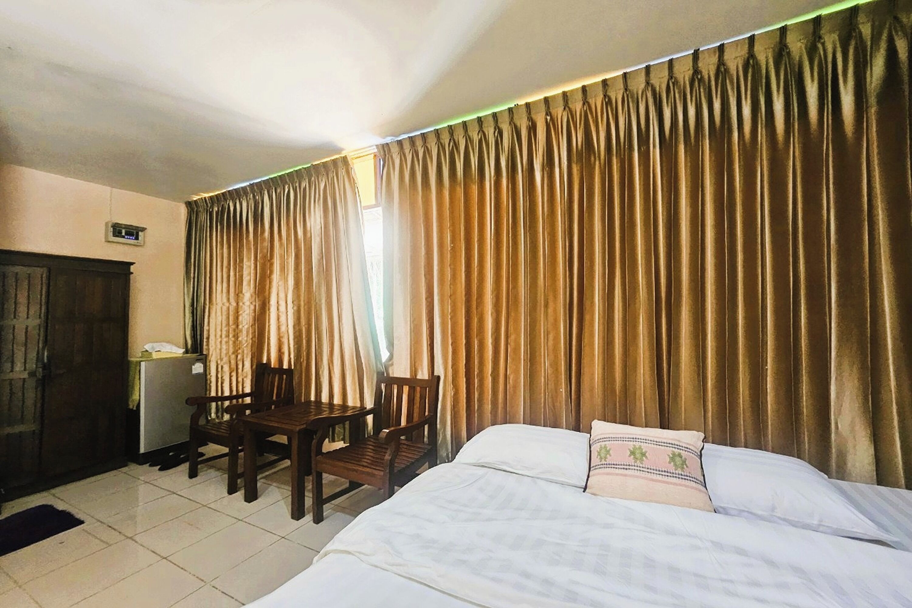 A hotel room with a bed, a desk, and a chair. There is a curtain on the window.