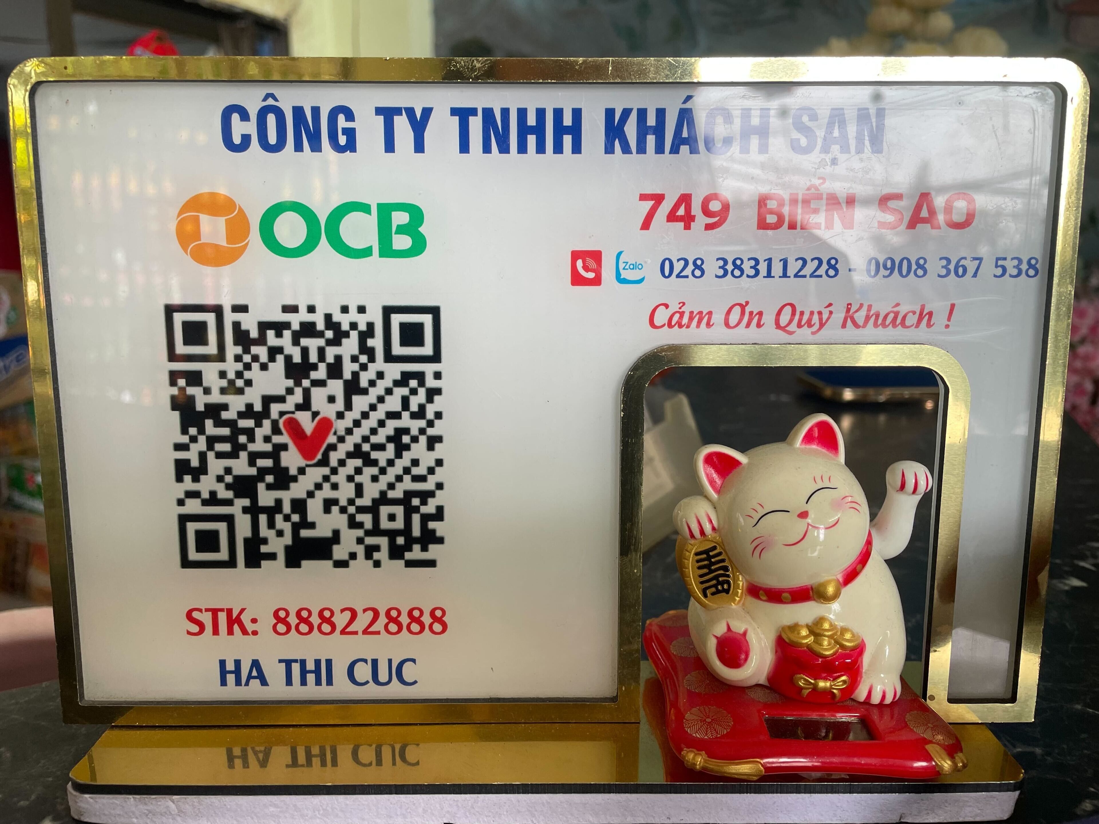 A sign with a QR code, a cat figurine, and contact information.
