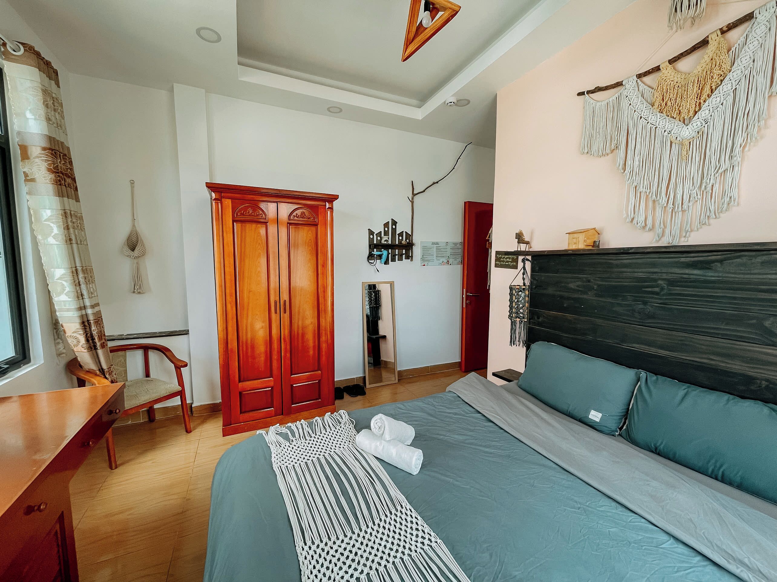 A bedroom with a bed, a wardrobe, a desk, and a mirror.