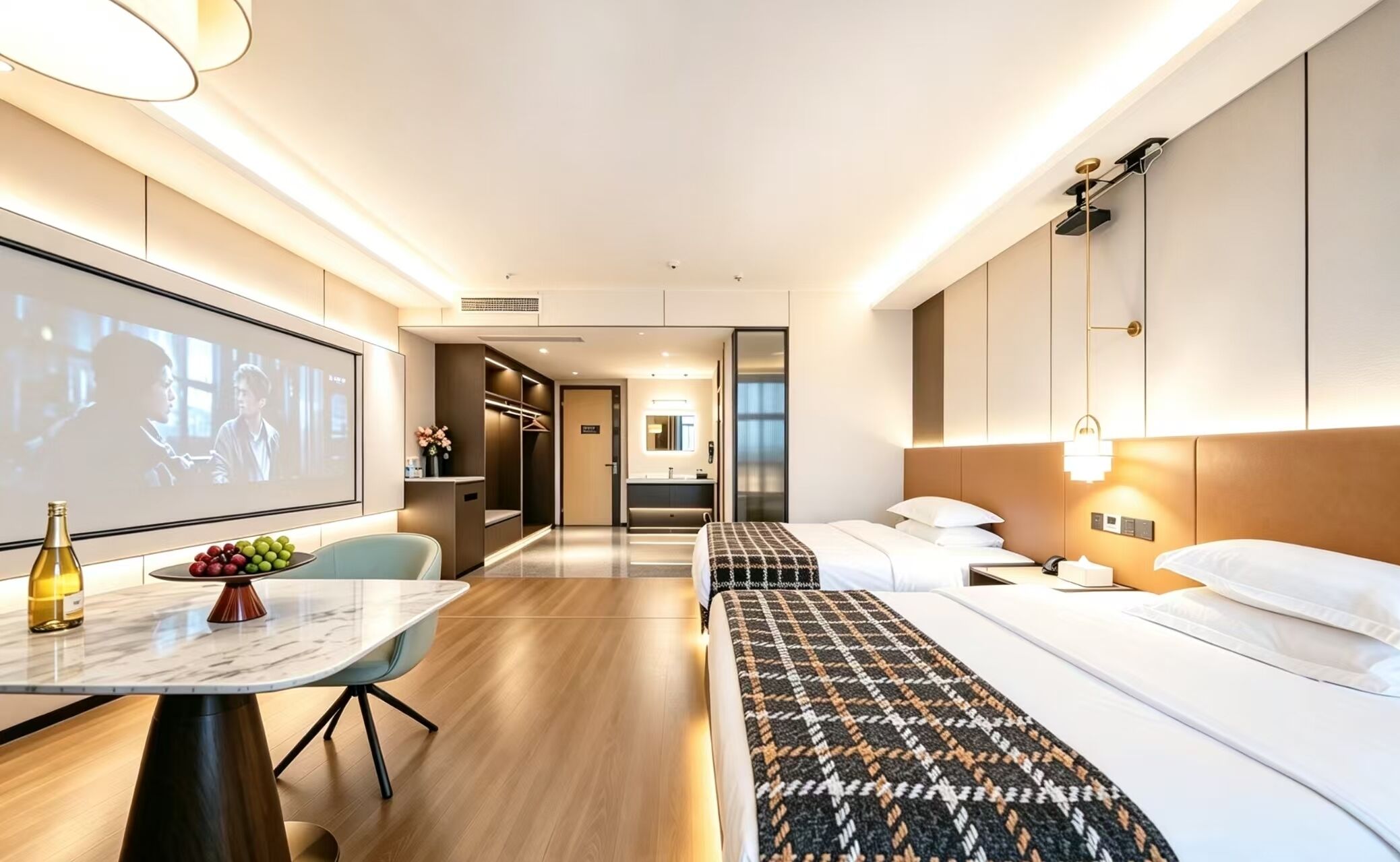 A modern hotel room with a bed, bedside table, and a large TV screen.