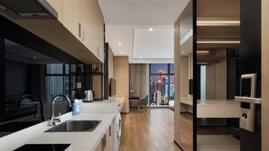A modern kitchen with a built-in oven, a sink, and a coffee machine. There is a dining area with a table and chairs. - Chongqing Sujiang Yunduan Riverview (Chongqing)
