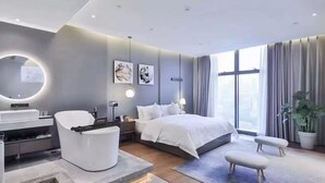A modern hotel room with a large bed, a round mirror, a desk with a chair, and a potted plant. - Chongqing Sujiang Yunduan Riverview (Chongqing)