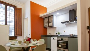 Uma cozinha compacta com área de refeições, com máquina de café, chaleira e torradeira.