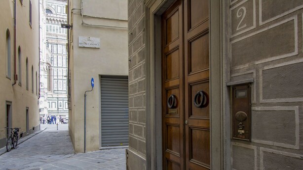 Uma rua de paralelepípedos estreita com uma porta de madeira e um toldo fechado.