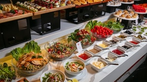 Un buffet proposant une variété de plats, notamment des salades, des viandes et des sauces.