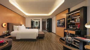 Une chambre d’hôtel moderne dotée d’un grand lit, d’un coin salon, d’un minibar et d’une salle de bain avec un miroir.