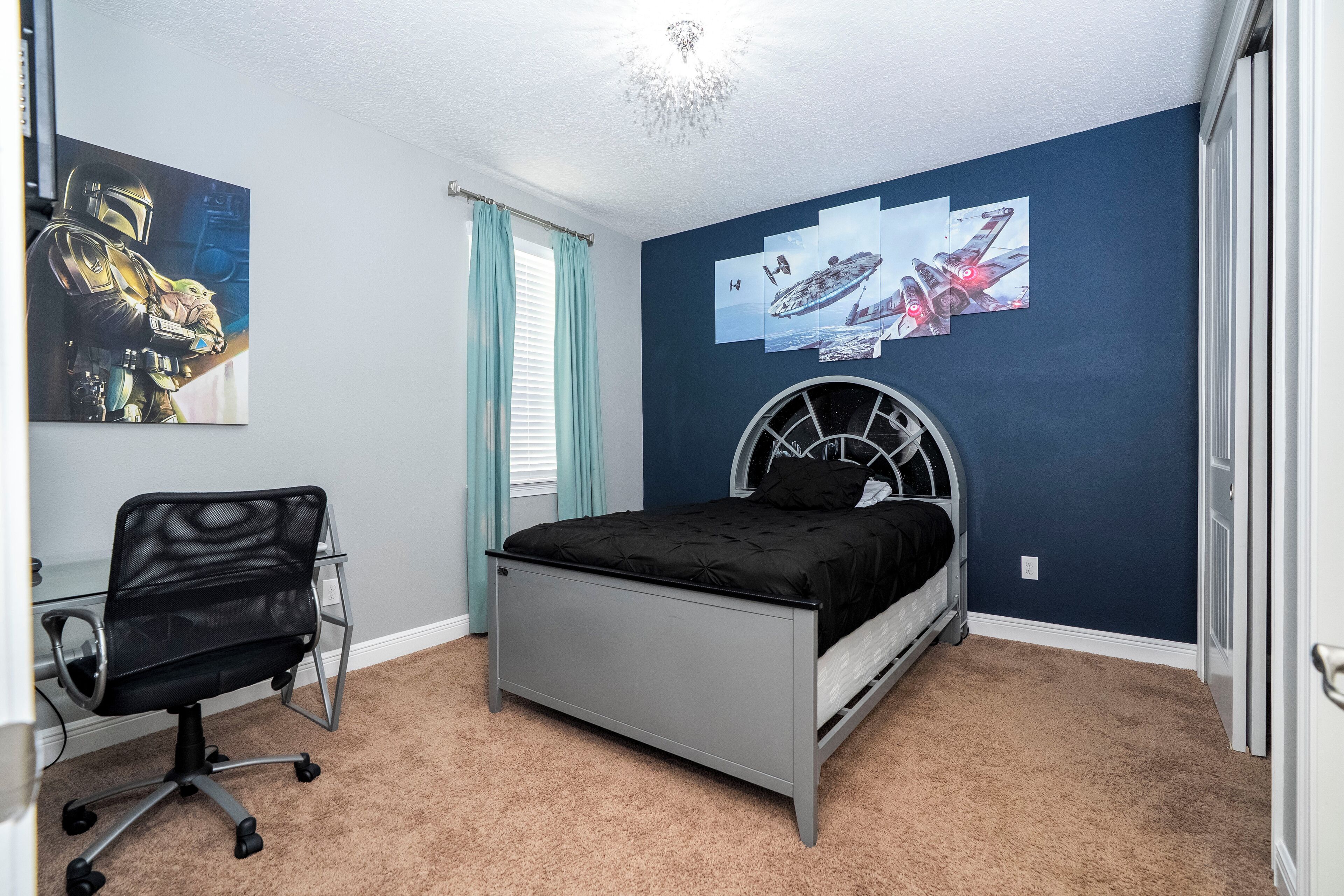 A bedroom with a bed, a desk, and a chair.