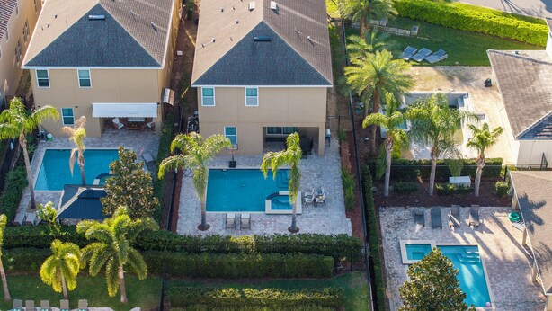 A multi-story residential building with a rooftop pool, palm trees, and a well-maintained lawn. - Classic 8-bedroom house with AC, WiFi in Kissimmee - Encore Reunion (Kissimmee)