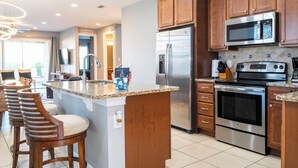 A modern kitchen with wooden cabinets, stainless steel appliances, and a central island with bar stools. - Classic 8-bedroom house with AC, WiFi in Kissimmee - Encore Reunion (Kissimmee)