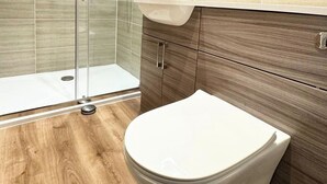 Une salle de bain moderne équipée de toilettes, d’une douche et d’un meuble-lavabo en bois.