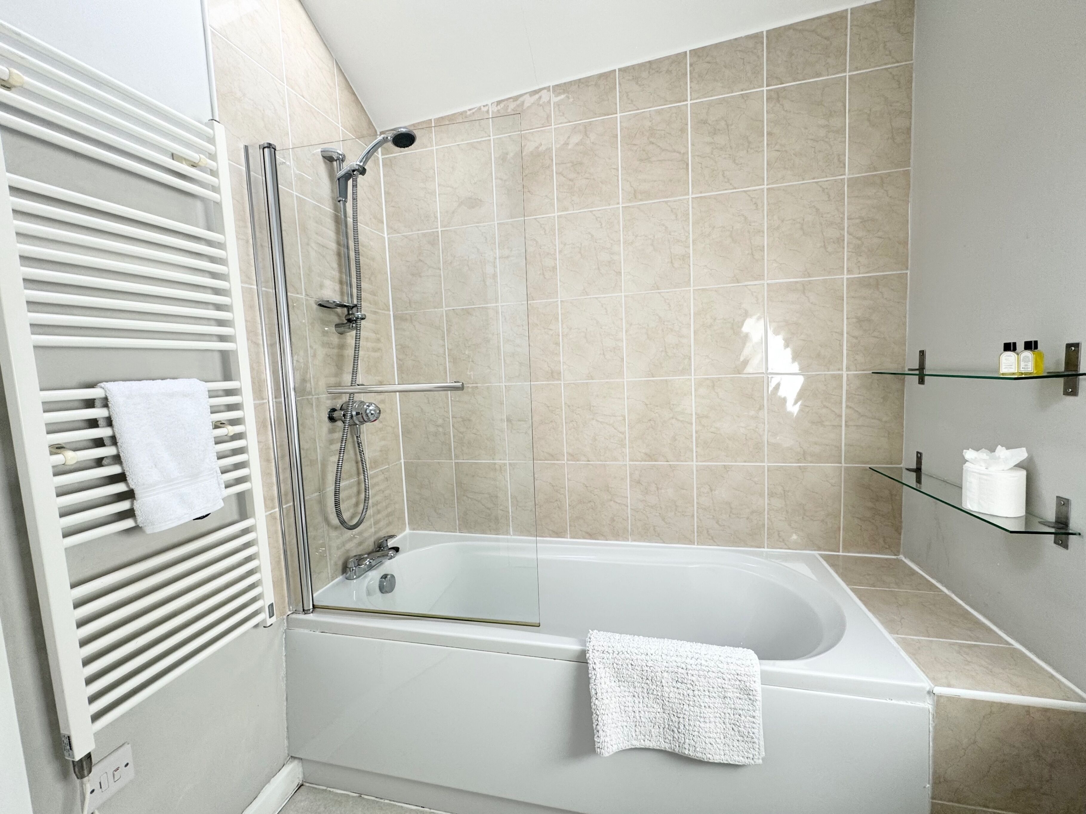 A modern bathroom with a bathtub, a shower, and a towel rack.