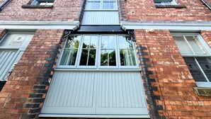 A multi-story brick building with a central entrance and large windows. - Warehouse Apartments (Ulverston)