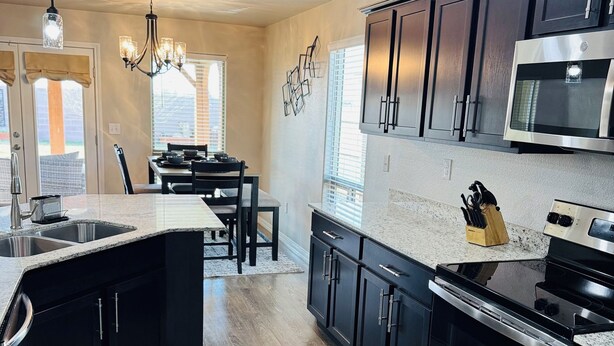 A modern kitchen with dark cabinetry, stainless steel appliances, and a central island.