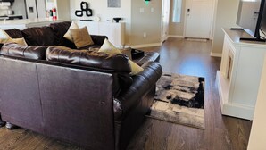 A modern living room with a leather sofa, a patterned rug, and a television on a stand.