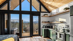 Una cucina moderna con travi in legno, ampie finestre e vista sulle montagne.