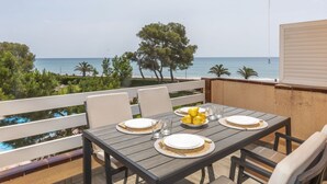 A table set for four with a view of the sea, a yellow umbrella, and a white railing.