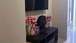 A modern living room with a flat-screen TV mounted on the wall, a black entertainment unit, a wooden side table, and a small desk. - Property near to Trident,Ayala,BGC and Airport and Supermarket & restaurant (Makati)
