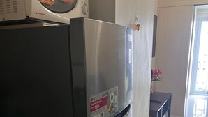 A kitchen with a stainless steel refrigerator, a microwave above it, and a small dining area with a table and chairs. - Property near to Trident,Ayala,BGC and Airport and Supermarket & restaurant (Makati)