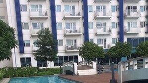 A swimming pool with a wooden deck and a bridge leading to a building with balconies. - Property near to Trident,Ayala,BGC and Airport and Supermarket & restaurant (Makati)